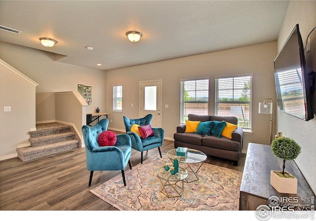 living room featuring stairway, baseboards, wood finished floors, and visible vents