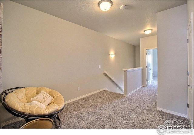 living area featuring carpet flooring, baseboards, and an upstairs landing