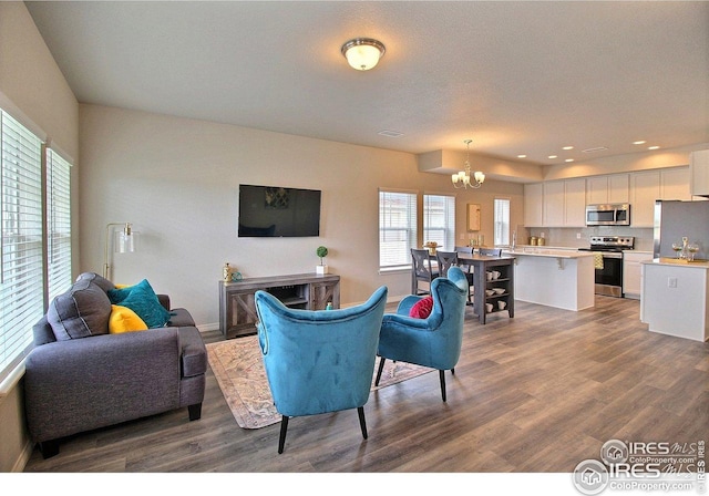 living room with dark wood-type flooring, a healthy amount of sunlight, a notable chandelier, and recessed lighting