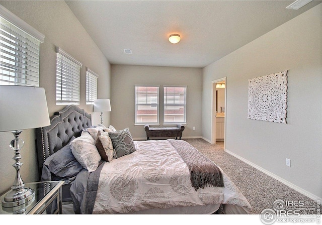 carpeted bedroom featuring connected bathroom, baseboards, and visible vents