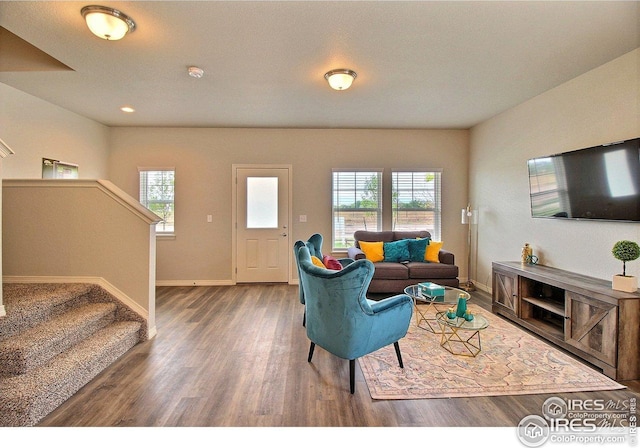 living area featuring baseboards, wood finished floors, a healthy amount of sunlight, and stairs