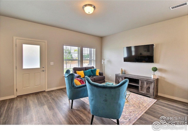 living area with baseboards, wood finished floors, and visible vents