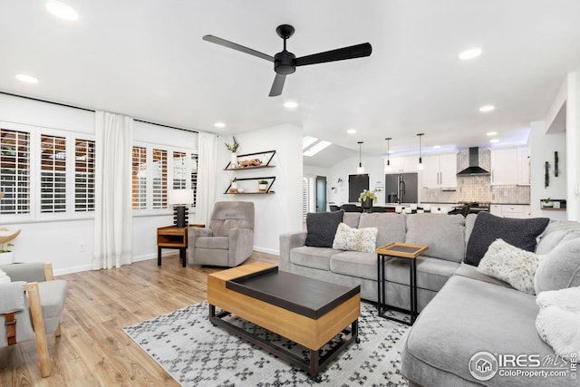 living area featuring baseboards, recessed lighting, light wood-style floors, lofted ceiling, and a ceiling fan