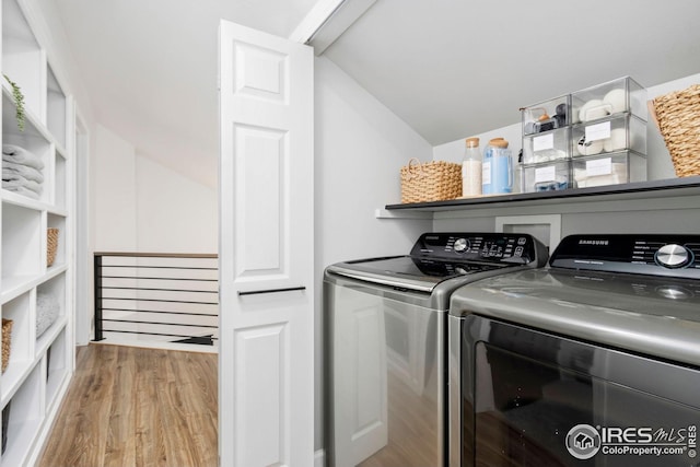 laundry room with washing machine and dryer, wood finished floors, and laundry area