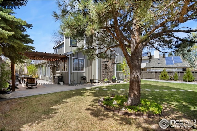 exterior space featuring fence, a pergola, a yard, board and batten siding, and a patio area