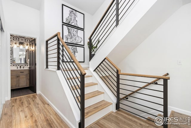 stairway featuring baseboards, wood finished floors, and a chandelier