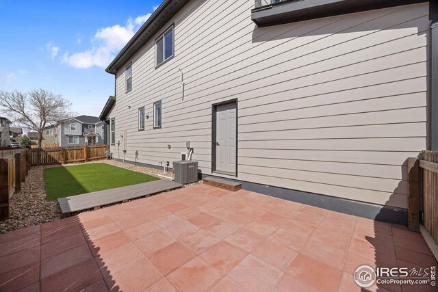 rear view of property with central air condition unit, a yard, a patio area, and a fenced backyard