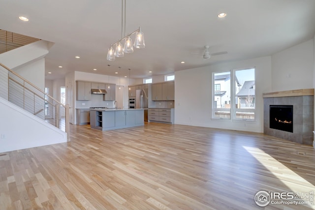 unfurnished living room featuring a fireplace, light wood-style floors, ceiling fan, and recessed lighting