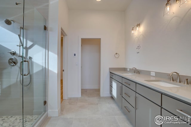 bathroom featuring tile patterned floors, a shower stall, double vanity, and a sink