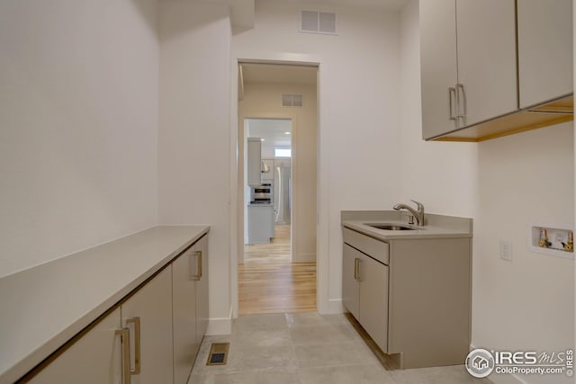 washroom with visible vents, hookup for a washing machine, cabinet space, and a sink