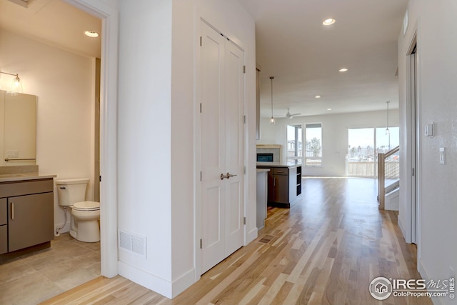 hallway with visible vents, recessed lighting, baseboards, and light wood-style floors