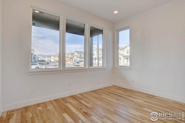 unfurnished room featuring wood finished floors, visible vents, recessed lighting, and baseboards