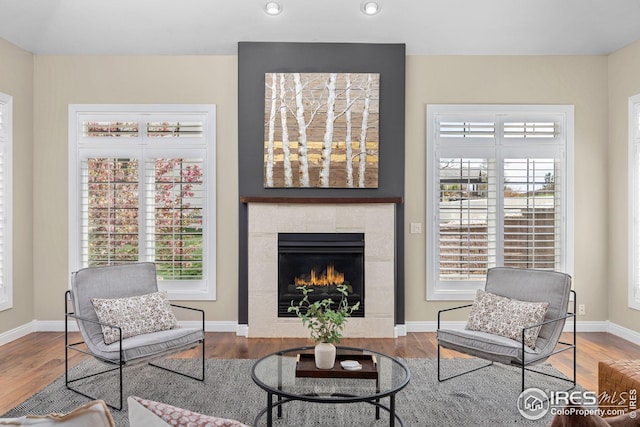 living area with baseboards, wood finished floors, a tile fireplace, and recessed lighting