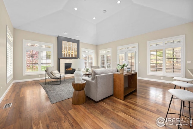 living room with wood finished floors, baseboards, and a lit fireplace