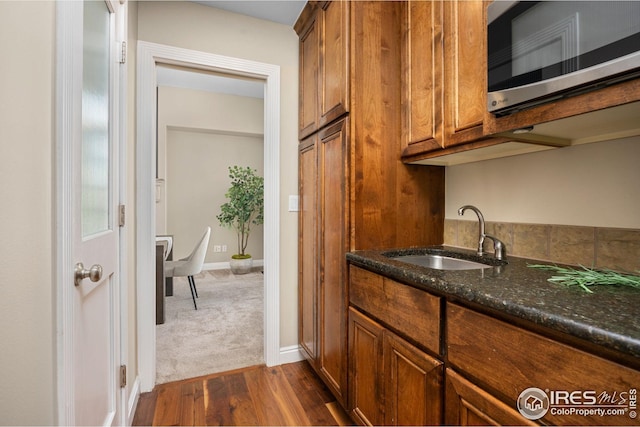 bar featuring stainless steel microwave, baseboards, a sink, and dark wood-style floors
