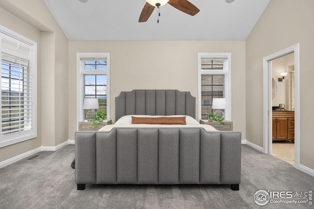carpeted bedroom with vaulted ceiling, a ceiling fan, ensuite bathroom, and baseboards