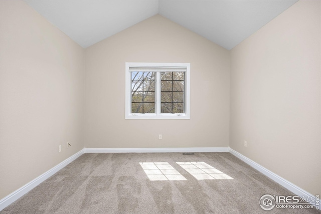 carpeted spare room with vaulted ceiling, visible vents, and baseboards