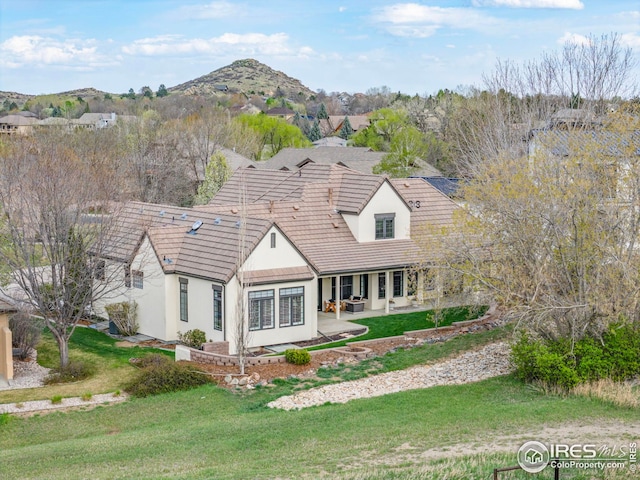 view of front of home featuring a patio, a tile roof, a front yard, and stucco siding