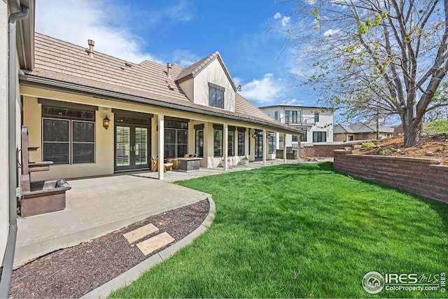 back of house featuring a patio area, a tile roof, and a yard