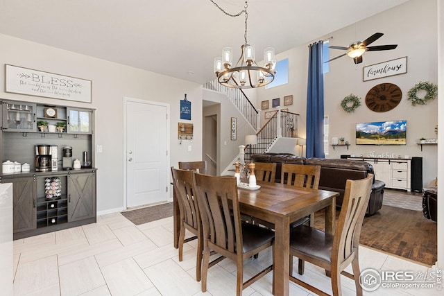 dining space featuring ceiling fan with notable chandelier and stairway