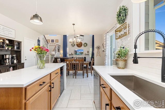 kitchen with pendant lighting, a notable chandelier, a sink, and light countertops