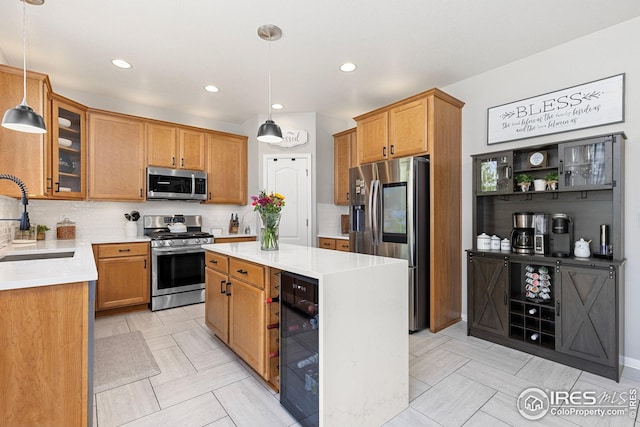 kitchen with a sink, beverage cooler, light countertops, appliances with stainless steel finishes, and a kitchen island