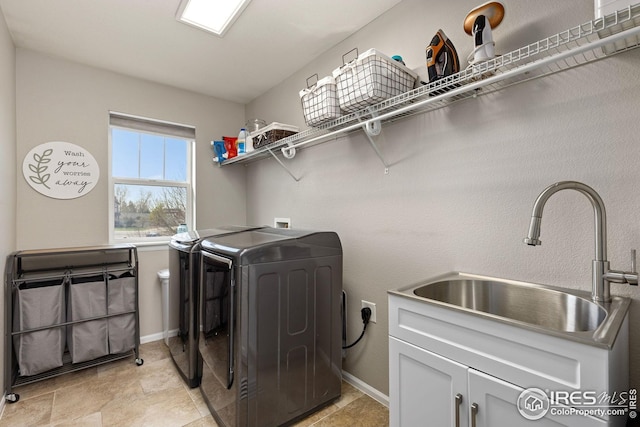laundry room featuring washing machine and dryer, baseboards, cabinet space, and a sink