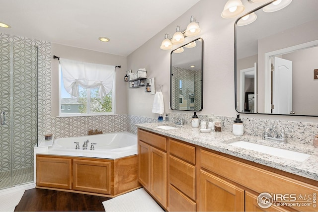 full bathroom featuring a bath, a stall shower, and a sink