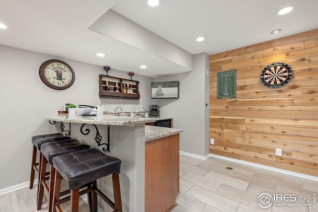bar featuring wooden walls, baseboards, recessed lighting, and wet bar