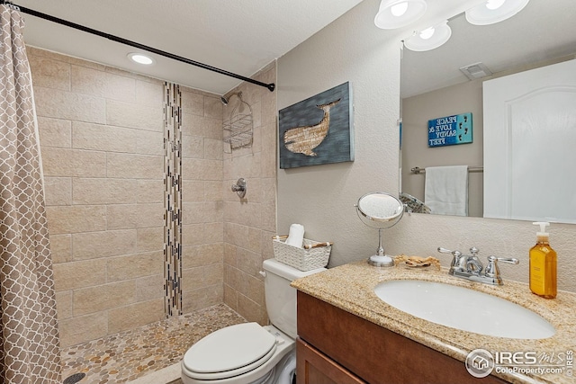 bathroom featuring a tile shower, toilet, and vanity