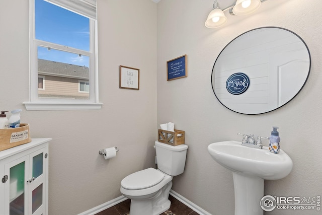 half bathroom with tile patterned flooring, toilet, and baseboards