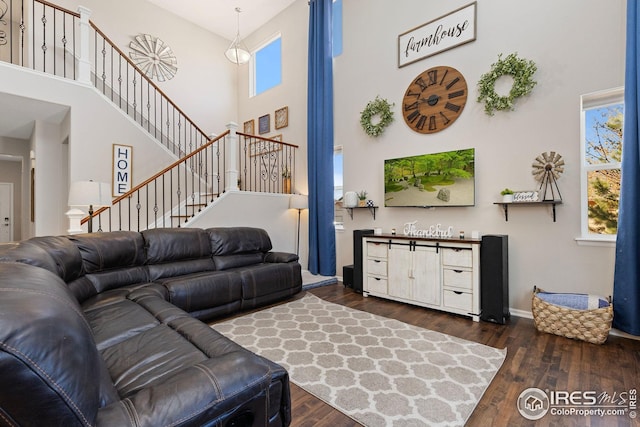 living area with baseboards, wood finished floors, a high ceiling, and stairway