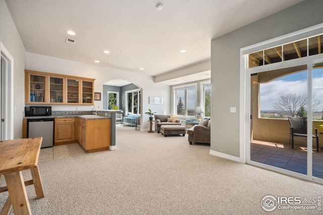 kitchen with arched walkways, open floor plan, light colored carpet, dishwashing machine, and black microwave