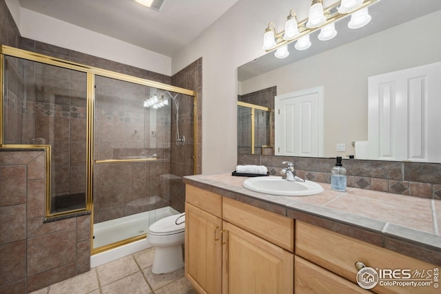 full bathroom featuring toilet, vanity, tile patterned floors, and a stall shower