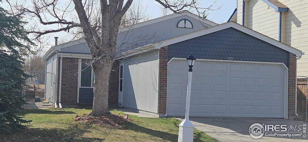 view of side of property with brick siding, an attached garage, and driveway