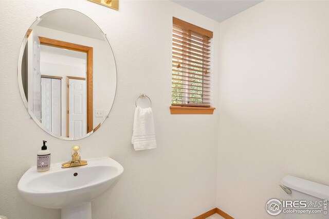 bathroom featuring toilet, a sink, and baseboards