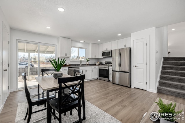 dining space with recessed lighting, baseboards, light wood-style flooring, a textured ceiling, and stairs