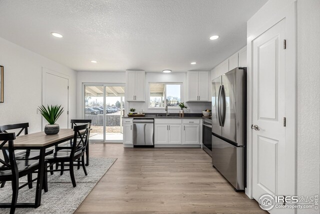 kitchen with recessed lighting, dark countertops, appliances with stainless steel finishes, and a sink