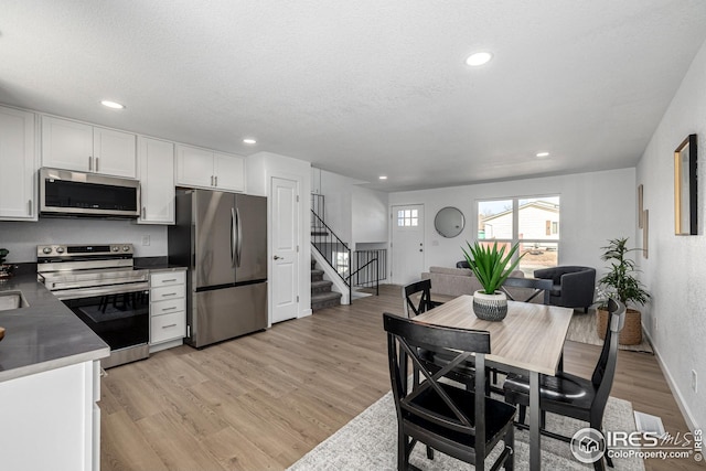 dining room with recessed lighting, stairway, baseboards, and light wood-type flooring