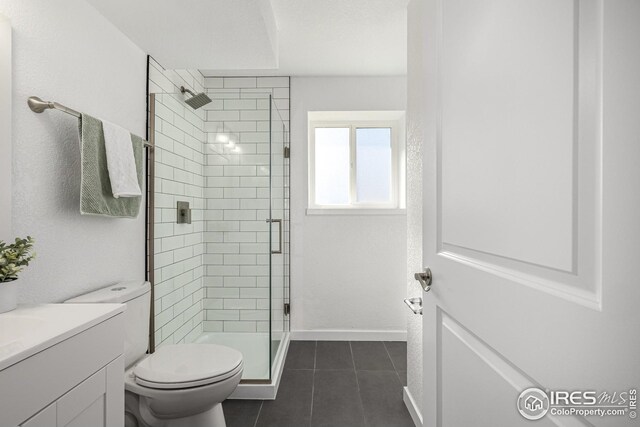 bathroom with a shower stall, tile patterned floors, vanity, baseboards, and toilet
