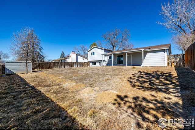back of house with an outbuilding and a fenced backyard