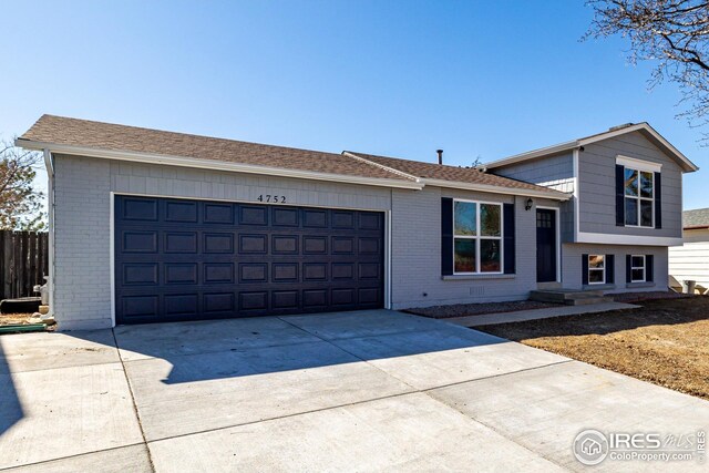 split level home featuring an attached garage, brick siding, and concrete driveway