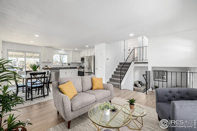 living area featuring recessed lighting, stairs, and light wood-style flooring