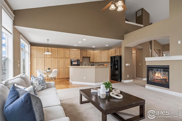 3122 Notabon Ct, Lafayette, CO 80026 - living area with high vaulted ceiling, arched walkways, a glass covered fireplace, a ceiling fan, and recessed lighting