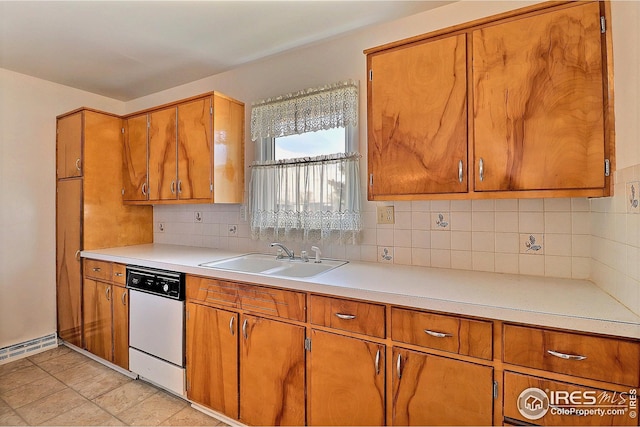 kitchen with brown cabinetry, light countertops, backsplash, dishwasher, and a sink