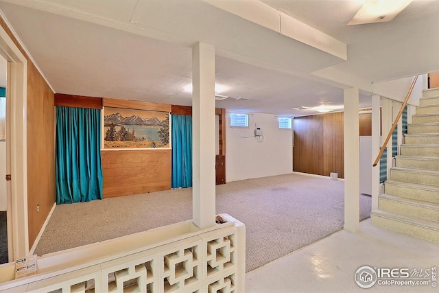 basement featuring stairway, wooden walls, and carpet flooring