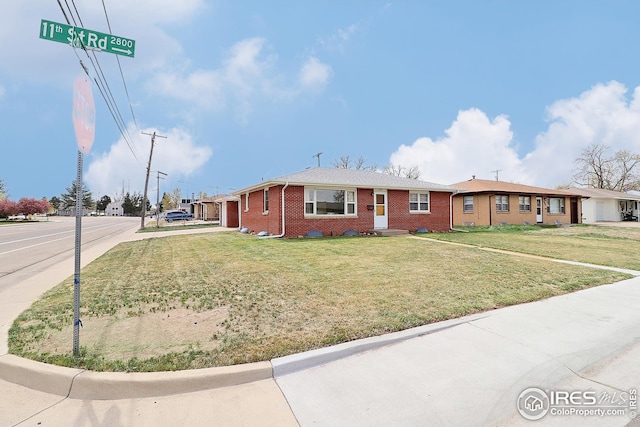 single story home featuring a front yard and brick siding