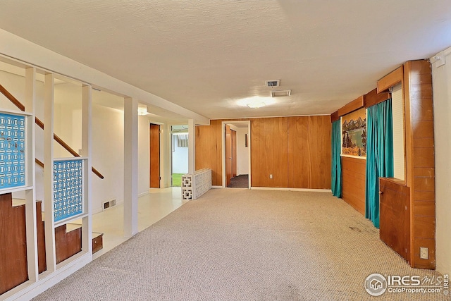 spare room featuring visible vents, wooden walls, and carpet