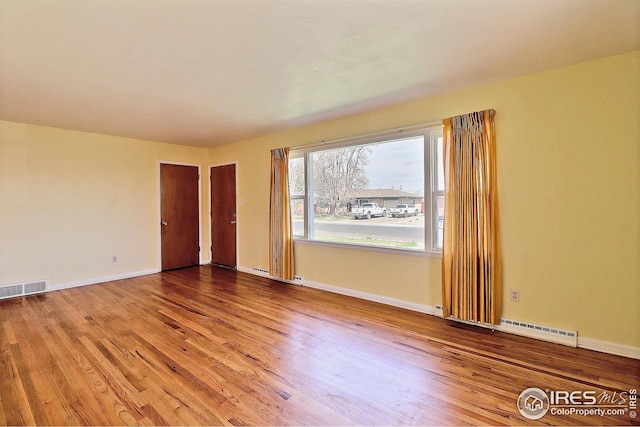 empty room featuring baseboards, visible vents, and wood finished floors