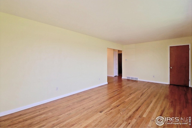 spare room featuring visible vents, light wood-style flooring, and baseboards